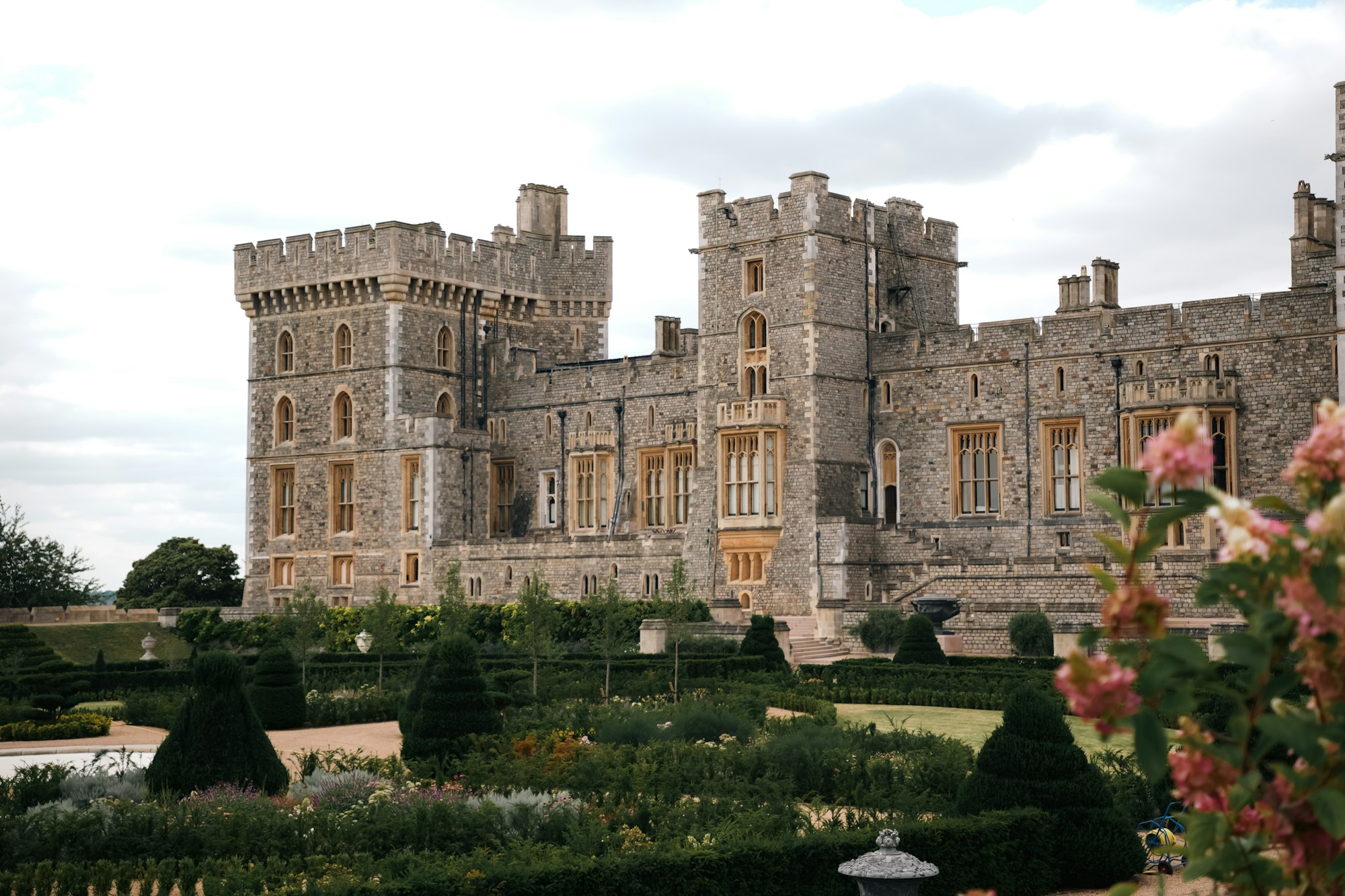 A historic castle surrounded by lush formal gardens at golden hour
